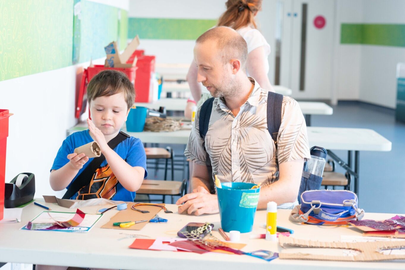 A man helps a young boy with a craft activity.