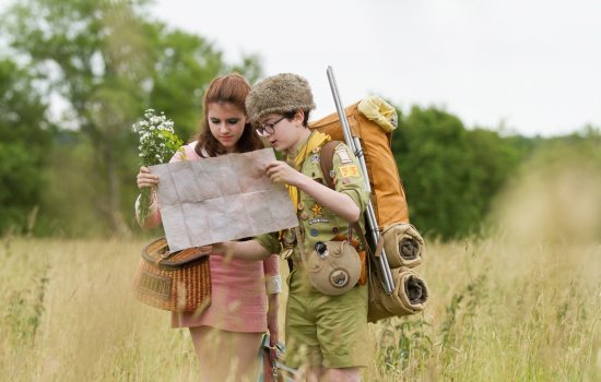 A young boy and girl stand in a field looking at a map