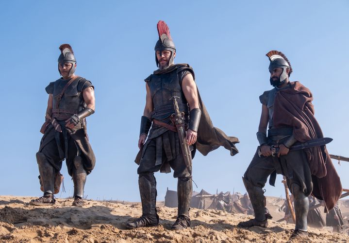 Three men dressed as ancient Greek soldiers, standing in a desert