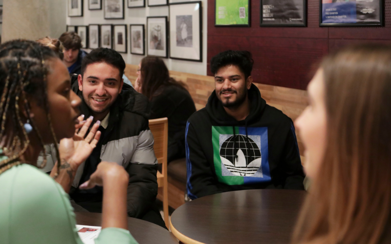 Young people sitting in the museum cafe, the focus is on two young boys listening to a woman talk