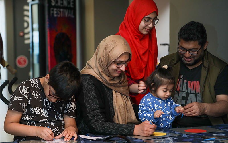 A family of South Asian origin doing activities at a Bradford Science Festival event in 2023