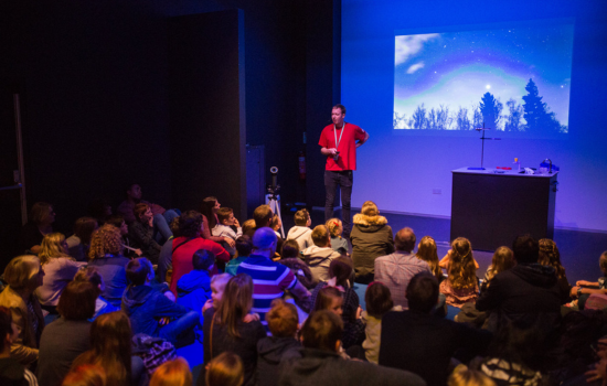 An image of an Explainer wearing a red tshirt conducting a live science show in Wonderlab Studio
