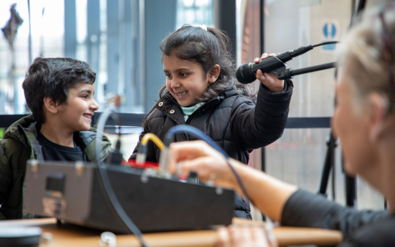 Children holding a microphone and using sound equipment