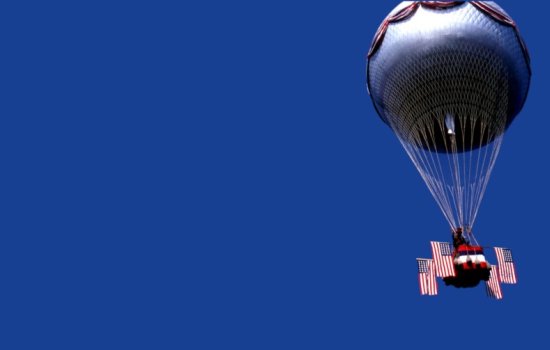 A hot hair balloon with four American flags set against a deep blue sky