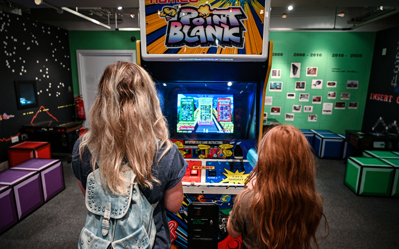 The backs of an adult woman and child's heads as they play on Point Blank in Games Lounge.
