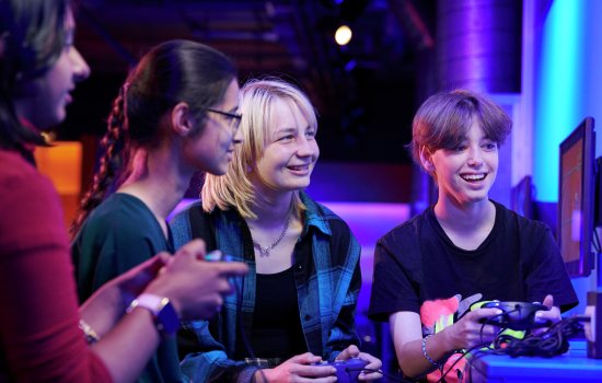A group of young people smiling and playing videogames