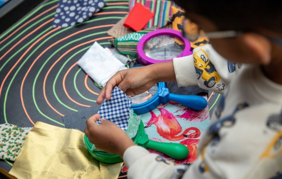 An image of a child doing an activity with fabric and magnifying glasses