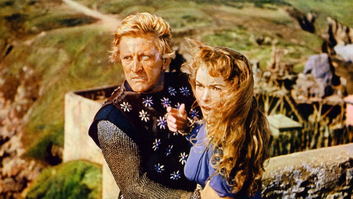 A scene from The Vikings featuring a man and woman on a ledge with a castle visible in the background.