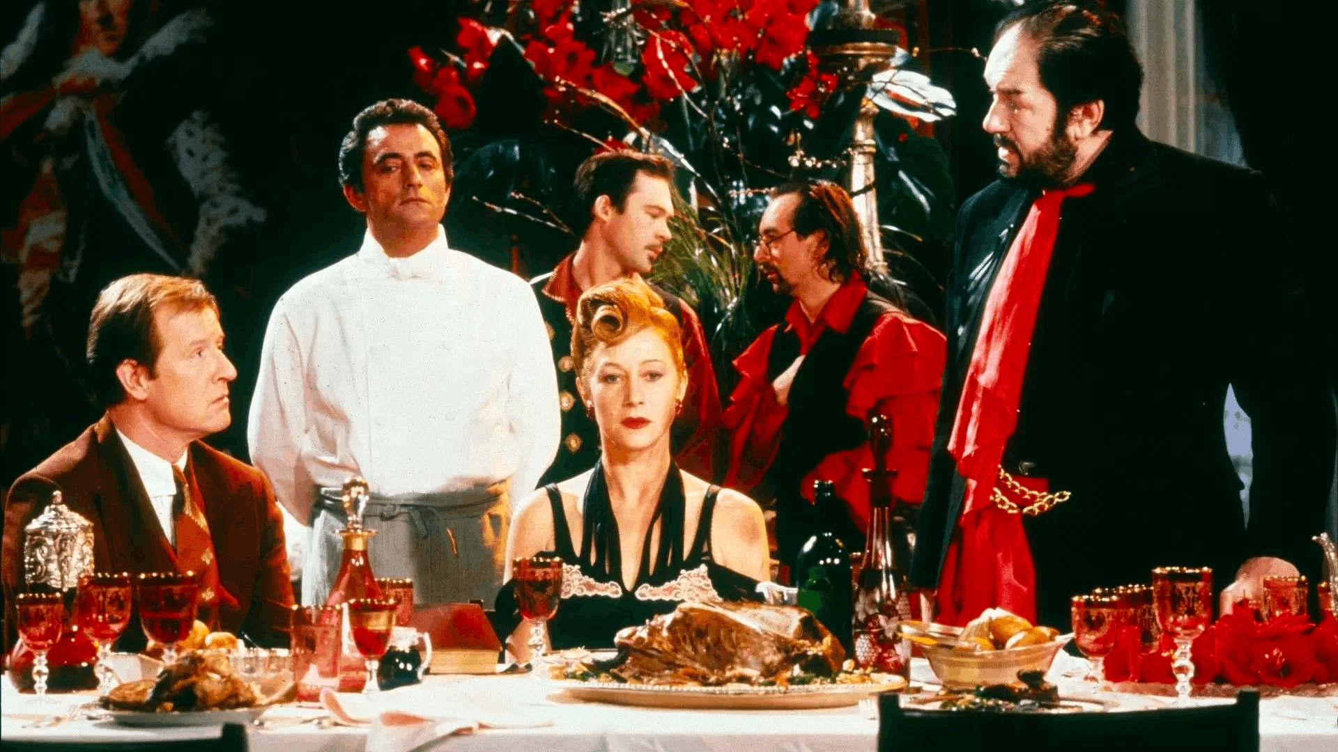 A still from The Cook, The Thief, His Wife and Her Lover featuring individuals gathered around a lavish table, prominently displaying a roasted turkey as part of their meal.