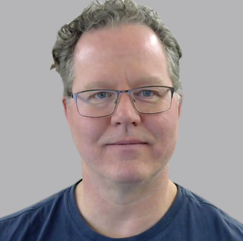 Image of a man with short hair wearing rectangular glasses and wearing a blue shirt.