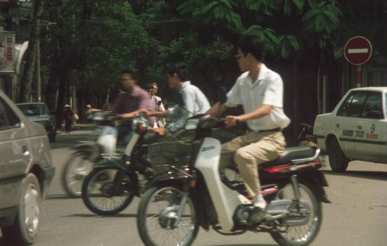 Men ride motorbikes on a busy road.