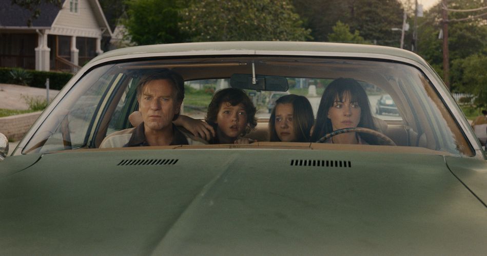 A family sit in a car, looking anxiously out.