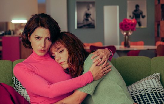 Two women embrace on a sofa