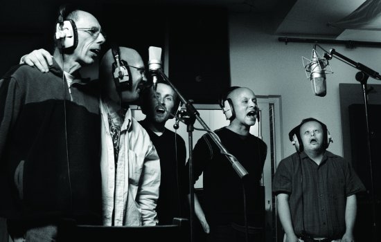 A group of men are singing in a recording studio.