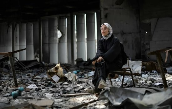 A woman sits in the middle of rubble.