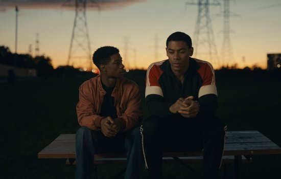 A still form the movie, Brother of two young men sat on a bench.