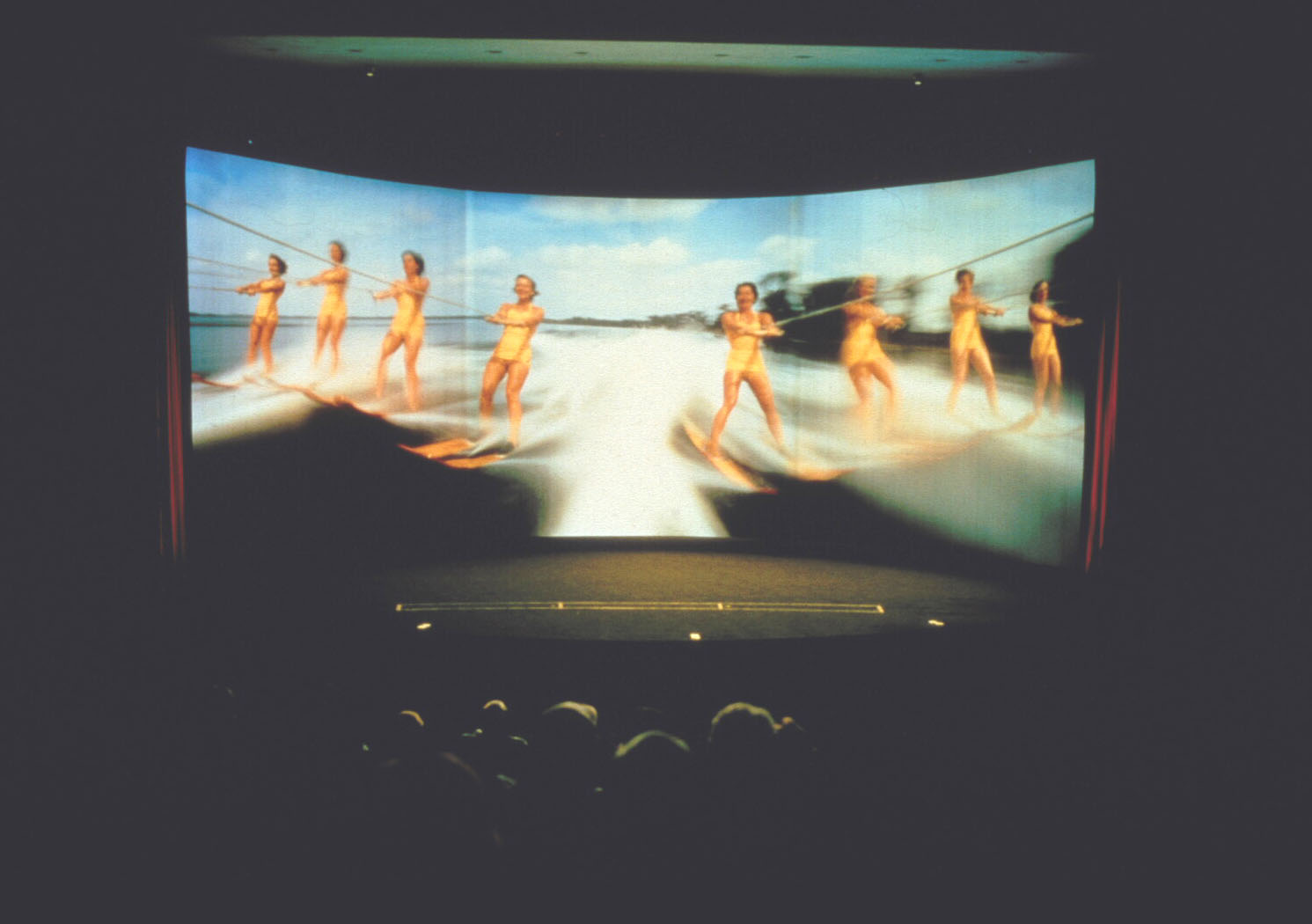 A point-of-view image of a rollercoaster ride with a cinema audience in the foreground