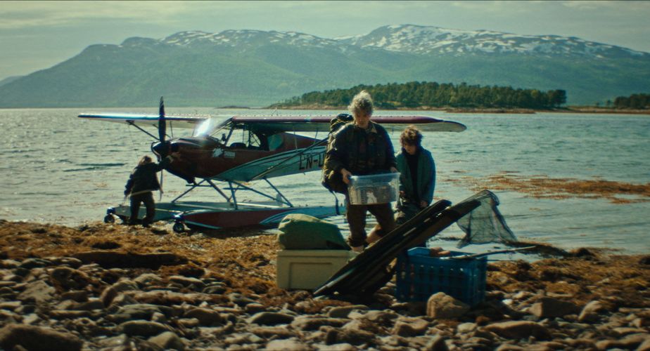 A man and a young boy unload equipment from a small plane