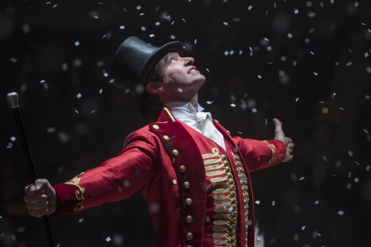 Hugh Jackman stands with arms outstretched as confetti showers down.