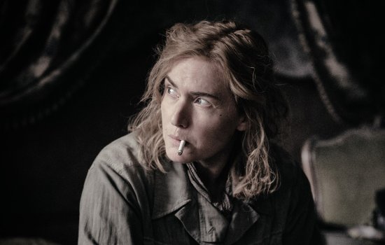 Kate Winslet sits with a cigarette, looking away from the camera with a determined expression.