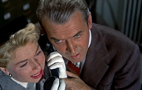 Cary Grant and Doris Day huddle around a phone.