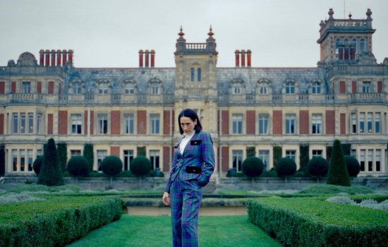 Sian Clifford stands in front of a large country estate.