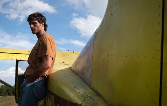Jacob Elordi leans against a small yellow plane.