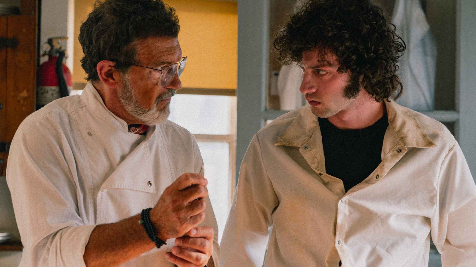 Dominic Sessa and Antonio Banderas stand side by side in chef's uniform.
