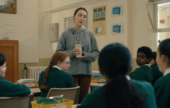 Saorise Ronan stands in the middle of a classroom.