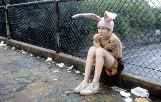 A still from Gummo featuring a young boy wearing rabbit ears, sat on a bridge.
