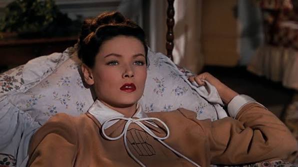 A woman reclines on a bed, staring passionately offscreen.