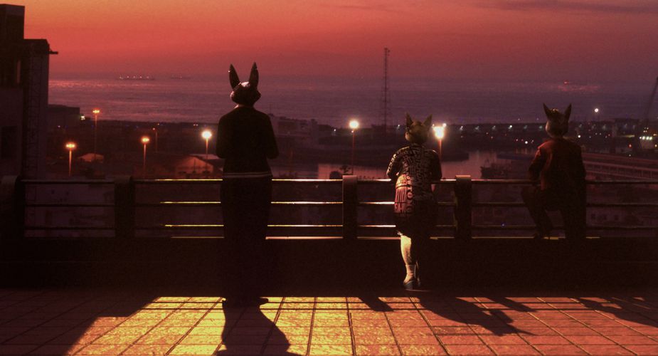 A  striking image of three dog-human figures looking out to sea.