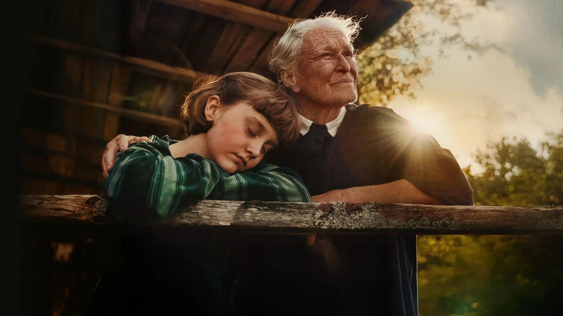 A still from The Summer Book in which Glenn Close embraces a young girl as the sun shines behind them.