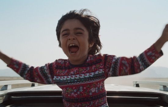 A young boy raises his arms