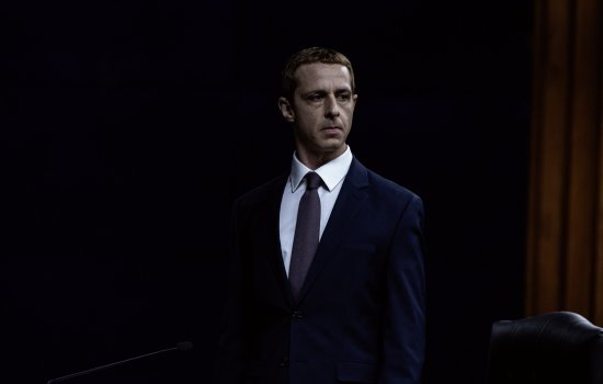 Callum Turner and George Mackay are dressed in yellow fisherman's coats, standing against the black night.