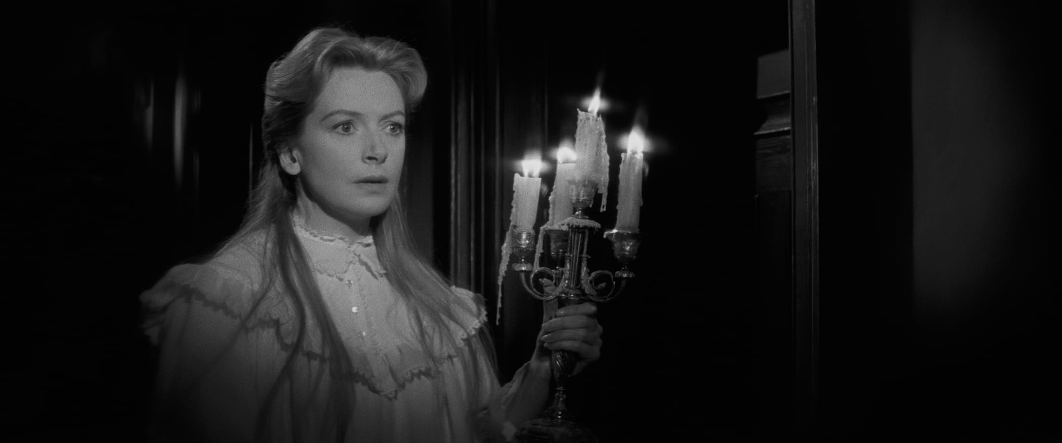 A black and white image of a woman holding a candlestick.