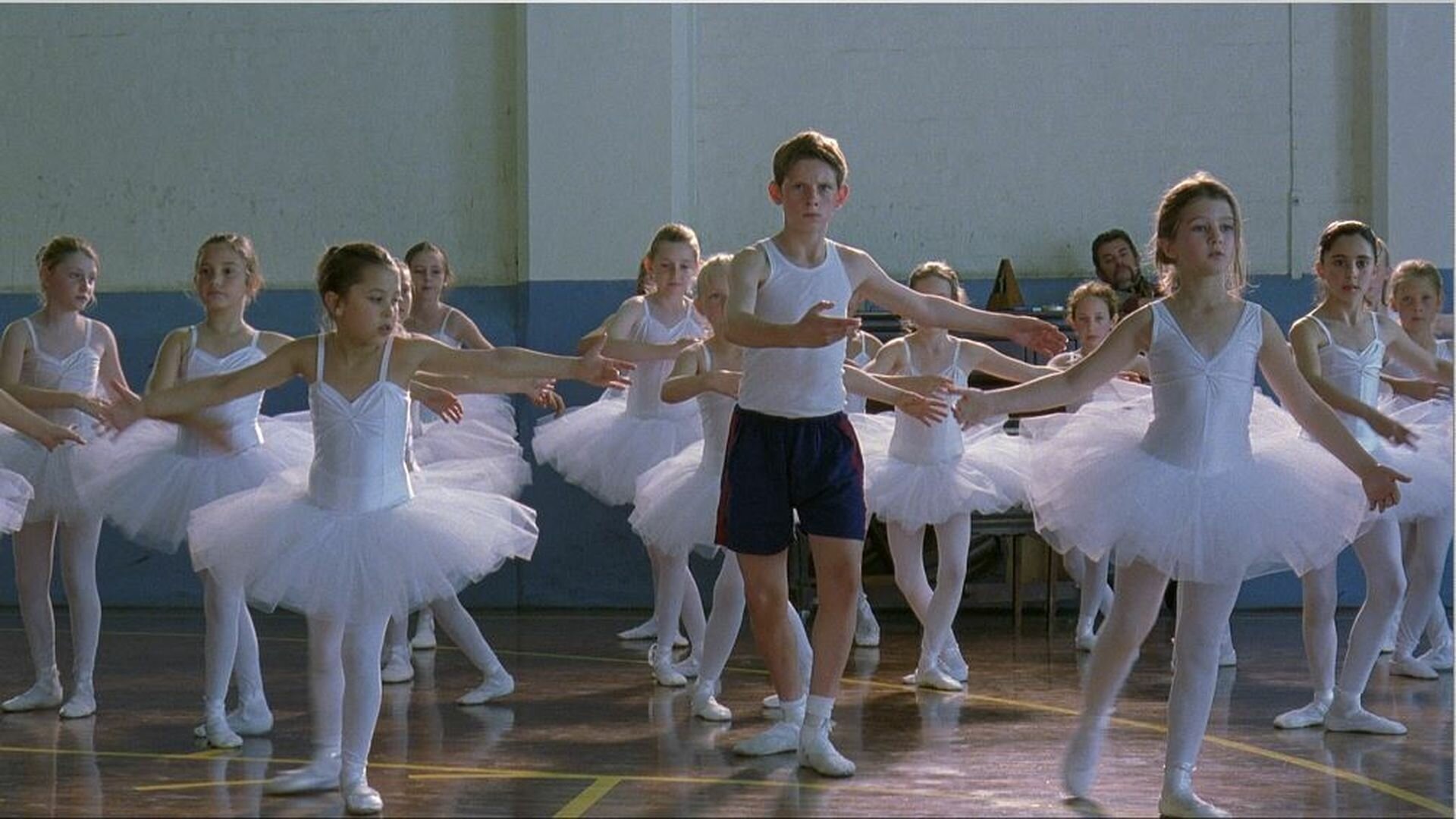 A young boy dances with a group of young girls dressed in ballet clothes