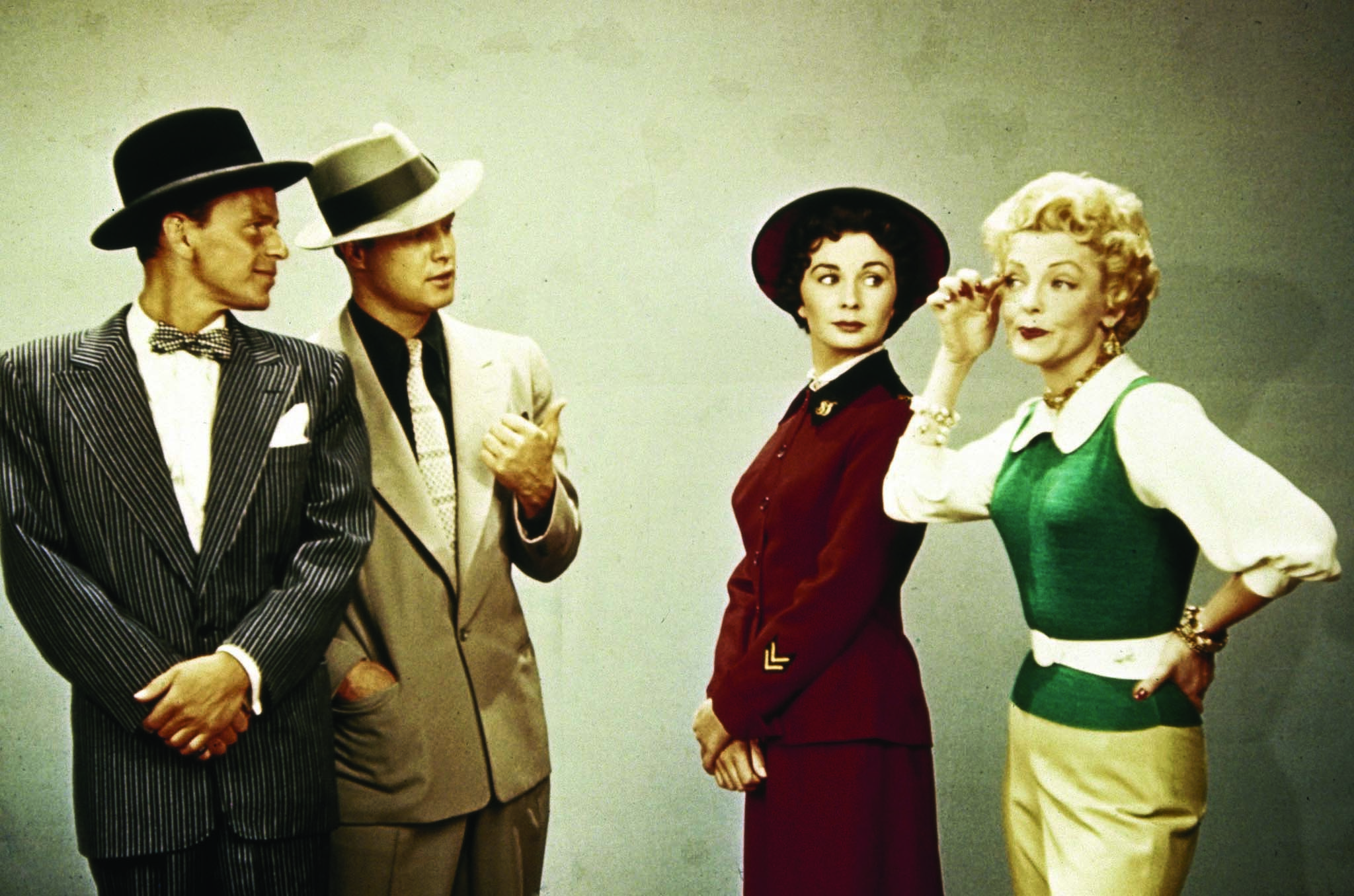 An image from Guys and Dolls featuring two suited men stood together staring at two women.