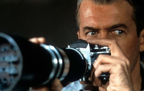 A still from Rear Window, featuring a close up of James Stewart pointing a large camera.