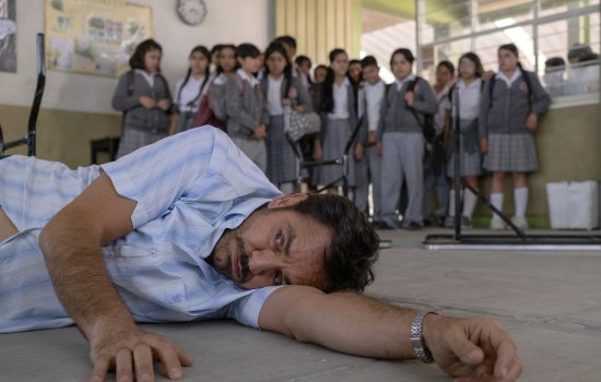 A man lays on the ground while a group of school children look on