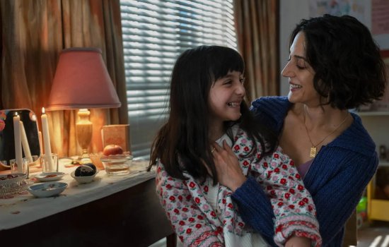 A woman and young girl embrace, smiling warmly at each other.