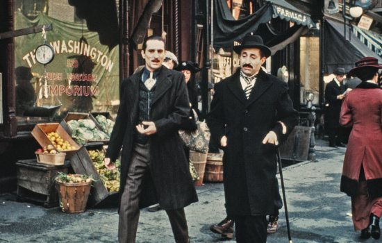 A still from The Godfather Part II of a young Robert De Niro walking through an old fashioned city, dressed in a suit.