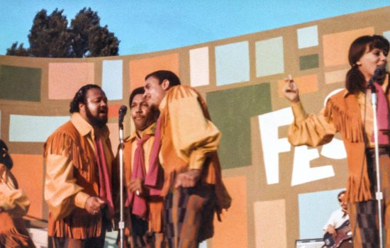 A group perform on an orange-coloured stage.