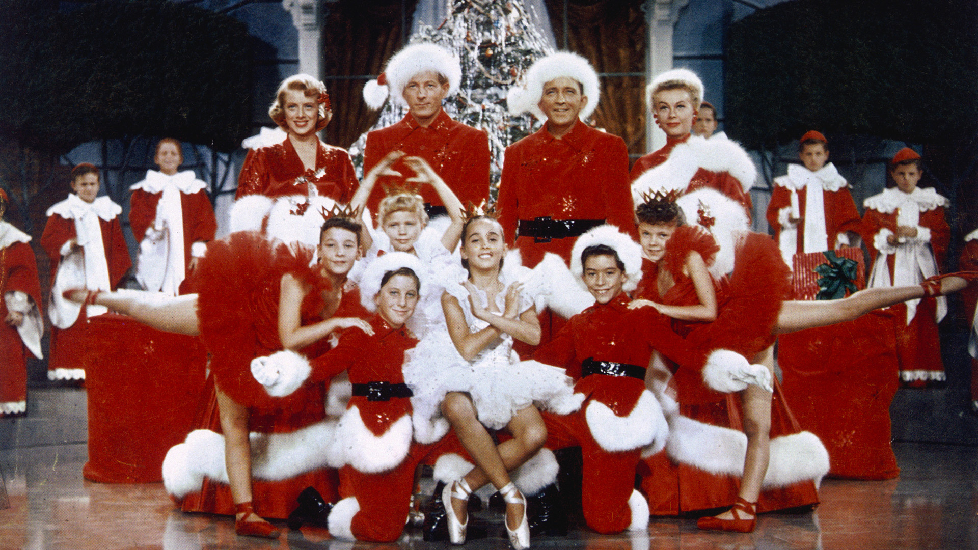 A group of performers wear bright red Christmas costumes.