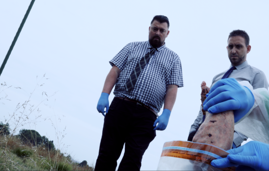 Two man stand on the moors wearing blue rubber gloves.