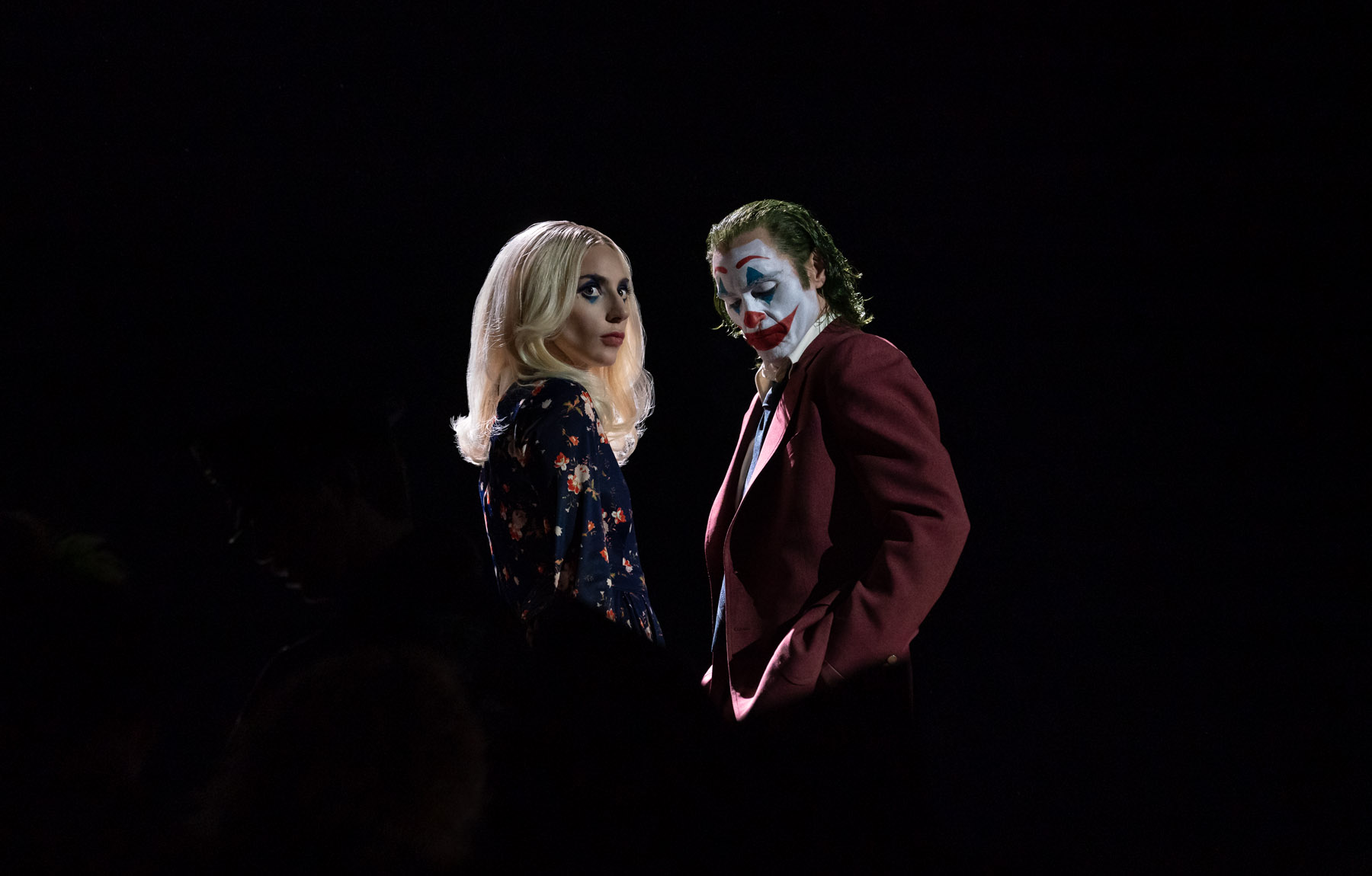 Lady Gaga and Joaquin Phoenix stand side by side with a completely black background.