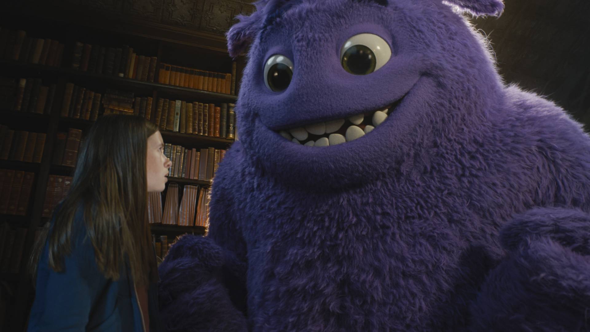 An image of a young girl stood with a large furry purple creature.