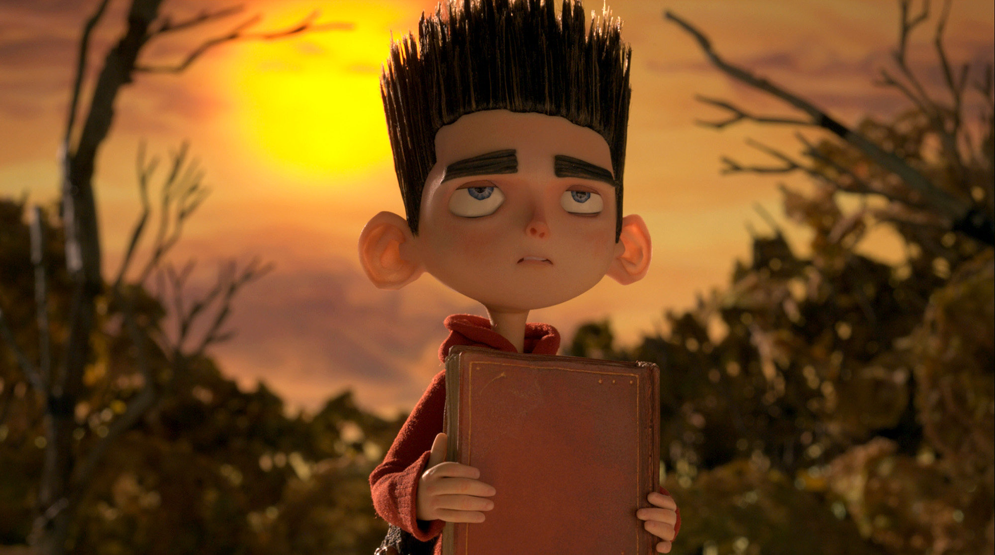 A stop-motion image of a young boy holding a large book.