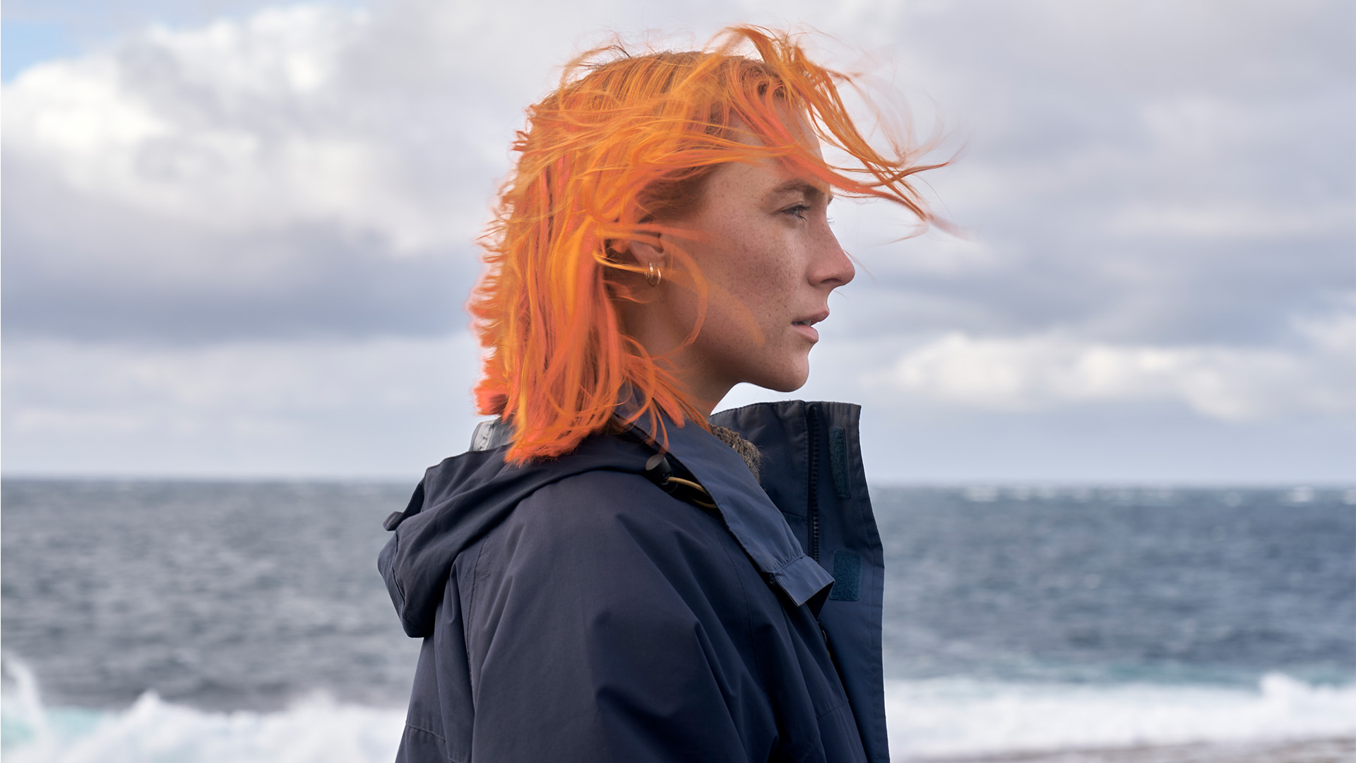 A profile image of Saorise Ronan with bright orange hair, with a grey backdrop.