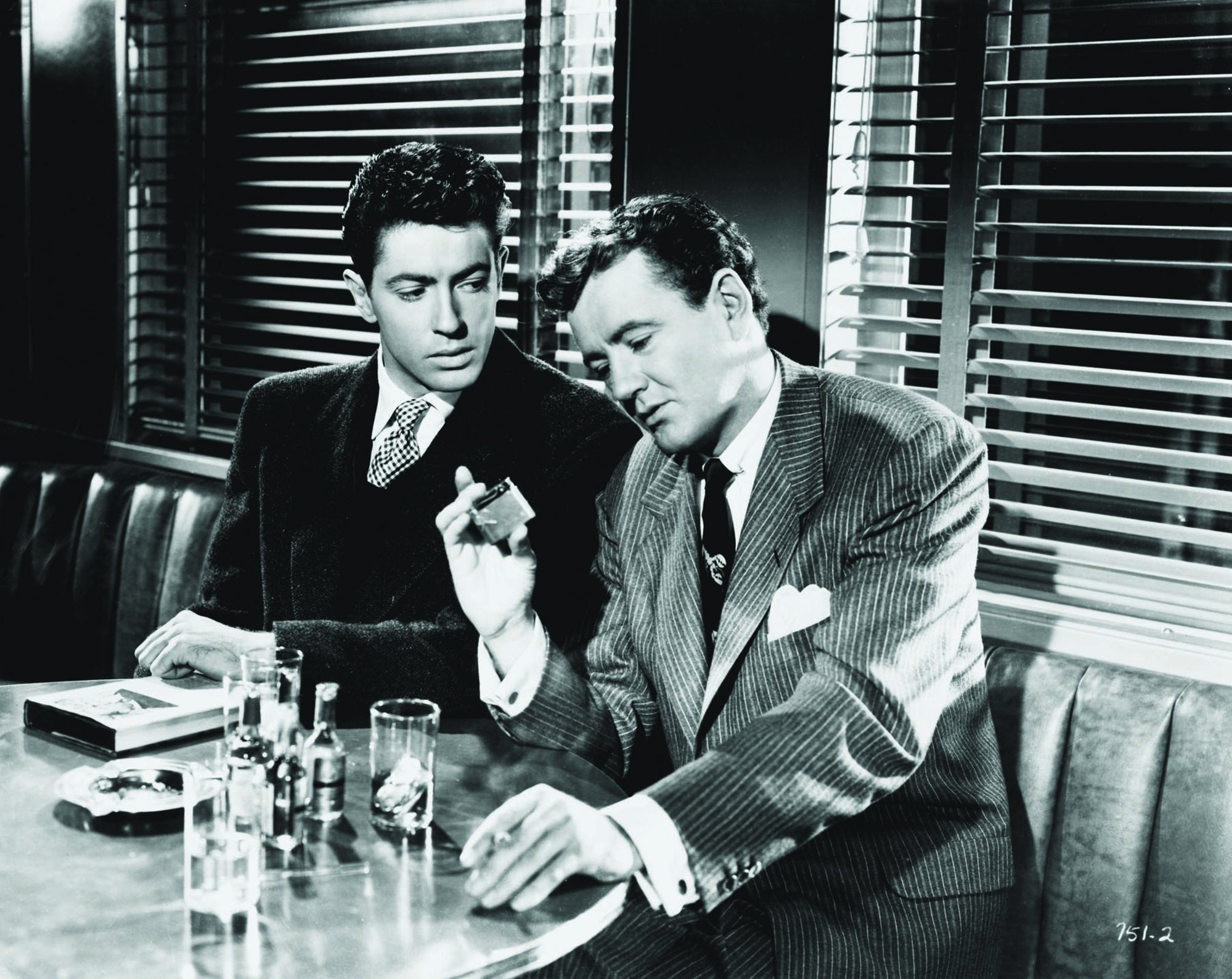 A black and white image of two men sat closely together, locked in serious conversation.